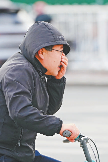 昨天，海澱區五道口，一位市民騎著自行車在風中出行。