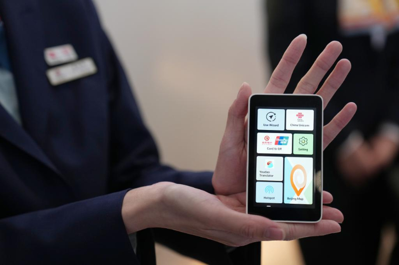 在北京首都國際機場T3航站樓的“北京服務”機場服務點,一位工作人員在展示“兩卡融合”終端。 在北京首都國際機場T3航站樓的“北京服務”機場服務點,一位工作人員在展示“兩卡融合”終端。