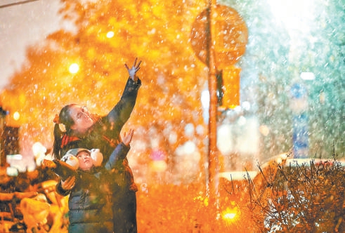 昨天，新年初雪飄落京城，在東單附近的胡同裏，一對母女興奮地與雪花共舞。